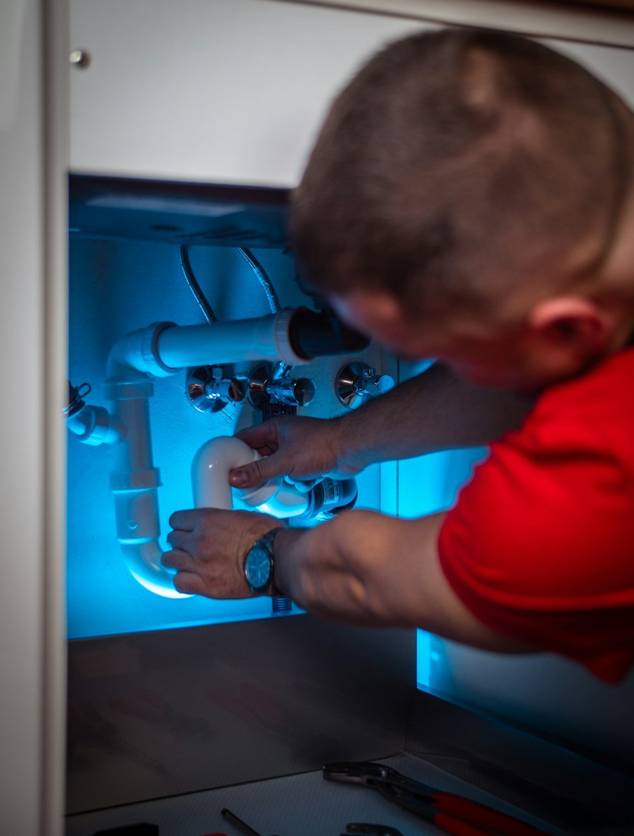Pine Rooter technician repairing a garbage disposal under a sink in Bothell, WA